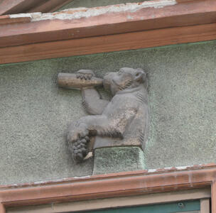 Stone carving above a window frame of bear drinking from a bottle
