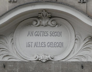Carved sign in oval scrollwork: AN GOTTES SEGEN IST ALLES GELEGEN