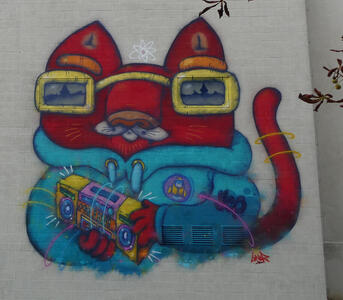 Wall painting of red cat wearing blue hoodie and yellow glasses, carrying a boom box