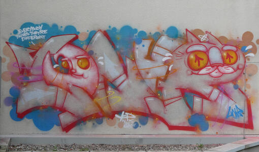 Wall graffiti. At left, the moon, saying “Everybody thinks they’re different”. At right, a cat with upward-pointing arrows for its pupils.