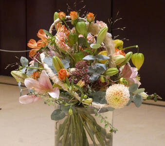 Arrangement of primarily orange flowers with some very small red flowers and large green leaves