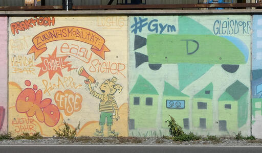 Left painting: a girl with a megaphone, with word Zukunftsmobilität and descriptive words: schnell, easy, sicher, für alle, praktisch, leise. At right, houses. One house has a window with two stick figures looking out of it. Above, a rocket with a D on it