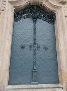 Bluish-green door with elaborate carving on handles and above the door frame