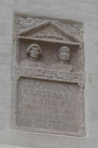 Weathered carving of two people; below it a Latin inscription