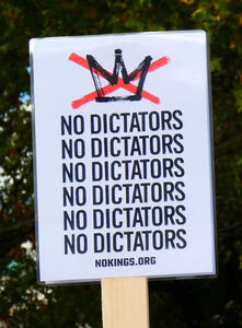 Crown with a red X through it. Below it, the phrase “NO DICTATORS” repeated vertically six times.