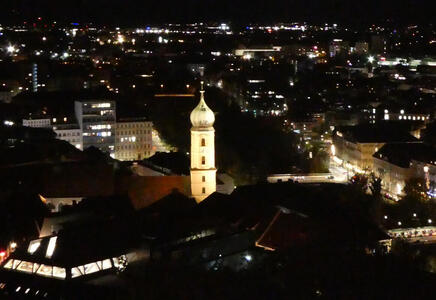 Nighttime view of Graz. An onion-dome church is illuminated.