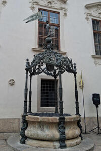 Well with wrought-iron cupola, atop is a knight holding a pennant