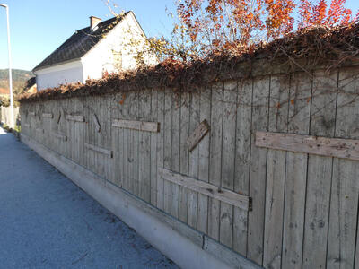 Wooden fence with added pieces of wood at angles to the fence slats.