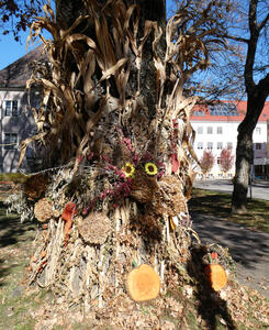 Tree decorated with flowers and stalks of plants.