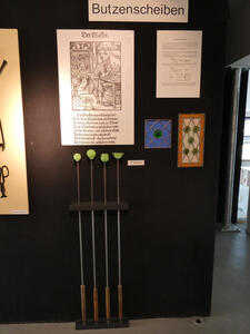 Display showing examples of bulls-eye panes (rectangular panes of glass with color bullseye patterns in them)