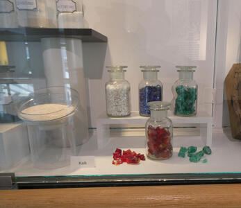 Display showing red, green, blue, and white glass crystals in jars
