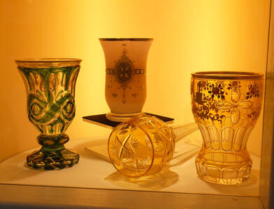 Four ornately designed drinking glasses. The one at left has green highlights.