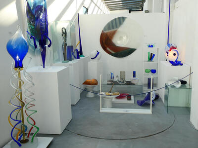 Large variety of glassware. At center back is a large disk with brown, green, and blue sectors.