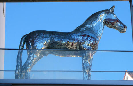 Sculpture of a horse covered in a mosaic of irregularly shaped mirrored tiles.