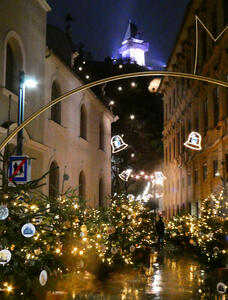 Archway at start of street; path is lined on both side with Christmas trees. The Uhrturm is in the background at the top.