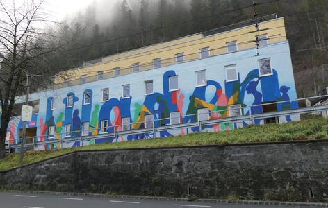 Blue building with silhouettes of people in many colors