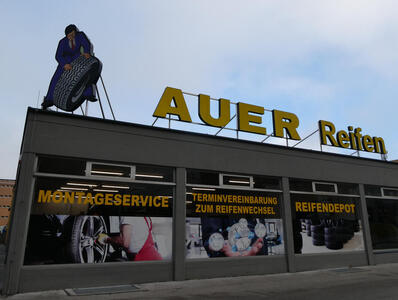 Tire service building; on roof, a large cutout of a man in a suit and tie holding a car tire.