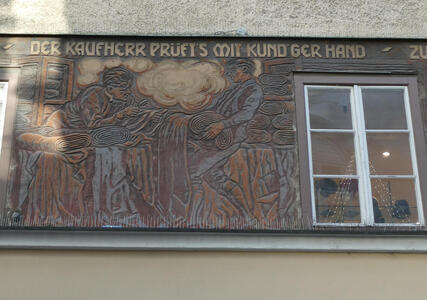 Merchant examining bolt of cloth. „Der Kaufherr prüft’s mit kund’ger Hand“