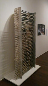 A frame of horizontal wooden rods with paint on them (as viewed from side)