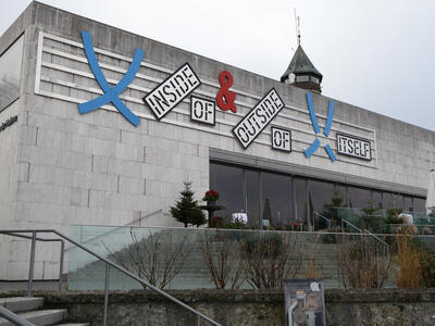 Artwork on modern art museum. Words in black stencilled text: “Inside of & Outside of Itself”