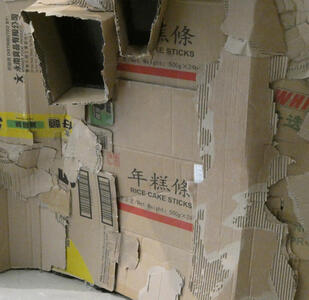 Closeup of room showing cardboard boxes of rice cake sticks and other boxes with chinese lettering