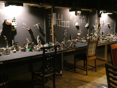 A workshop with tables covered in small cardboard sculptures.