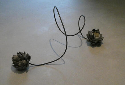 Two pieces of metal shaped like artichokes, connected by a looping metal cable