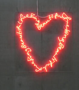 Neon sign in a heart shape; the neon spells out “fucking beautiful” in cursive several times.