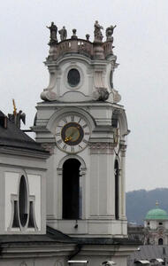 Clock tower. On top, statues of people facing outward on each of the four corners.