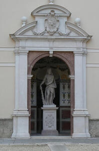 Arched entranceway; under the arch is a statue of person leaning on large club