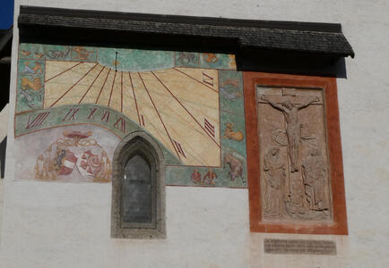 Sundial next to a reliefwork crucifixion scene