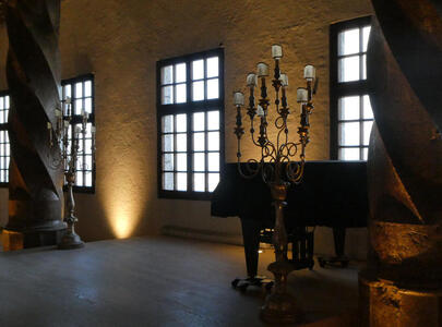 Room with paino at right; a floor-mounted candelabra is in front of the piano