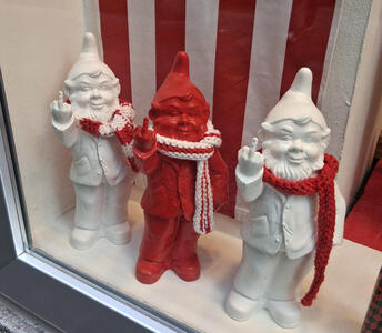 White, red, and white gnome figurines, each wearing a red and white scarf. They are all giving the finger.