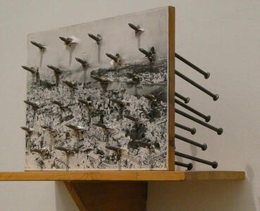 Photo of a city with spikes driven through it in a grid pattern. The points of the spikes are facing outwards towards the viewer.