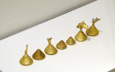 A row of small brass pieces that look like Hershey kisses.
