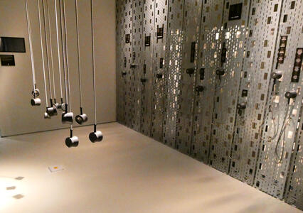 Headphones hanging from ceiling; on metal wall, an array of headphones with placards telling what sounds you will hear