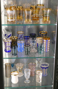 Three shelves of glassware; top shelf primarily gold tinted; bottom shelves priarily blue tinted
