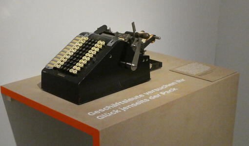 Old-style black adding machine with handle to activate the mechanism.