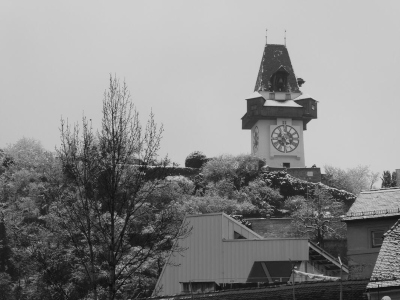 The Graz Clock Tower with a light dusting of snow. At left, trees with snow on them