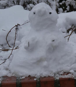 Very small snowman on brick wall.