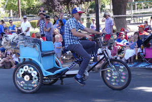 Man on bicycle rickshaw; wheels have CDs in spokes