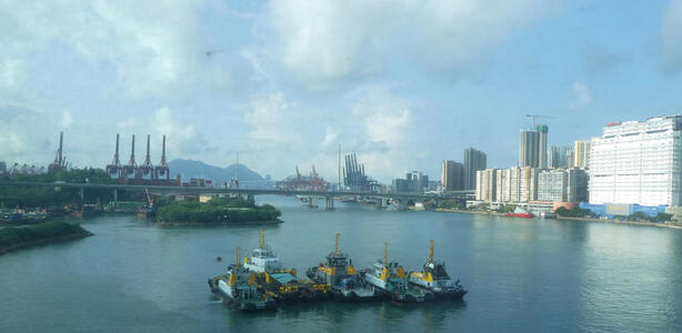 Boats in foreground; bridge in background. Large buildings at right.