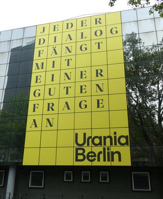 Yellow tiles with black print: Jeder Dialog fängt mit einer guten Frage an (Urania Berlin)