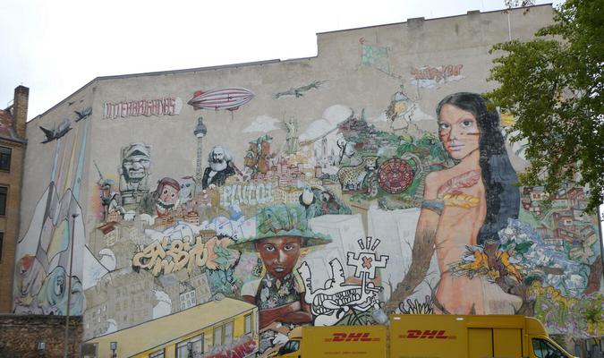 Multiple images including Karl Marx, the Berlin Tower, a black man with a green hat, and an indigenous Aztec/Mayan woman with tattoos.