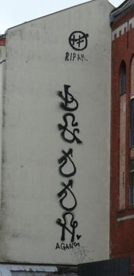 Abstract black letter-like symbols painted vertically on building wall.