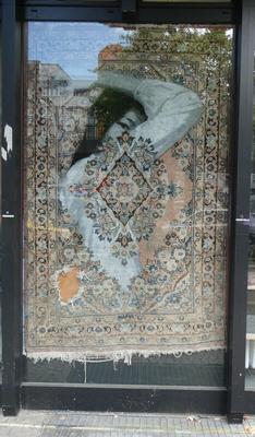 Persian Rug, transparent in places so you see an Asian woman with her arm folded above her head.