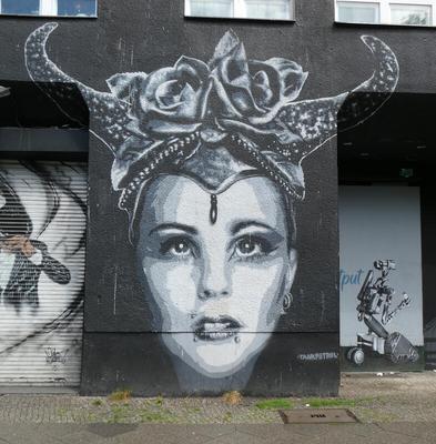 Woman with jewel on forehead, wearing a headdress with horns; there are roses  in the center