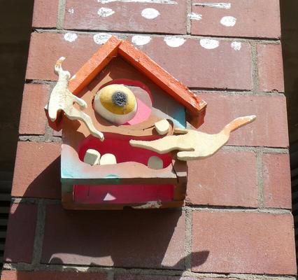 Abstract house with eye and teeth (wood sculpture attached to wall)