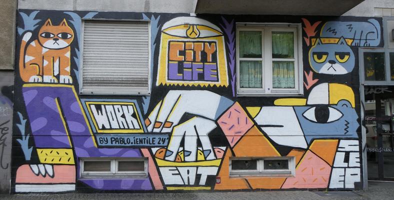 City Life; cartoonish animal eating from a bag of food, and two cartoonish cats with grim expressions at top left and right.