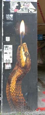 Gold serpent vertically painted on wall; its tongue is a match flame.